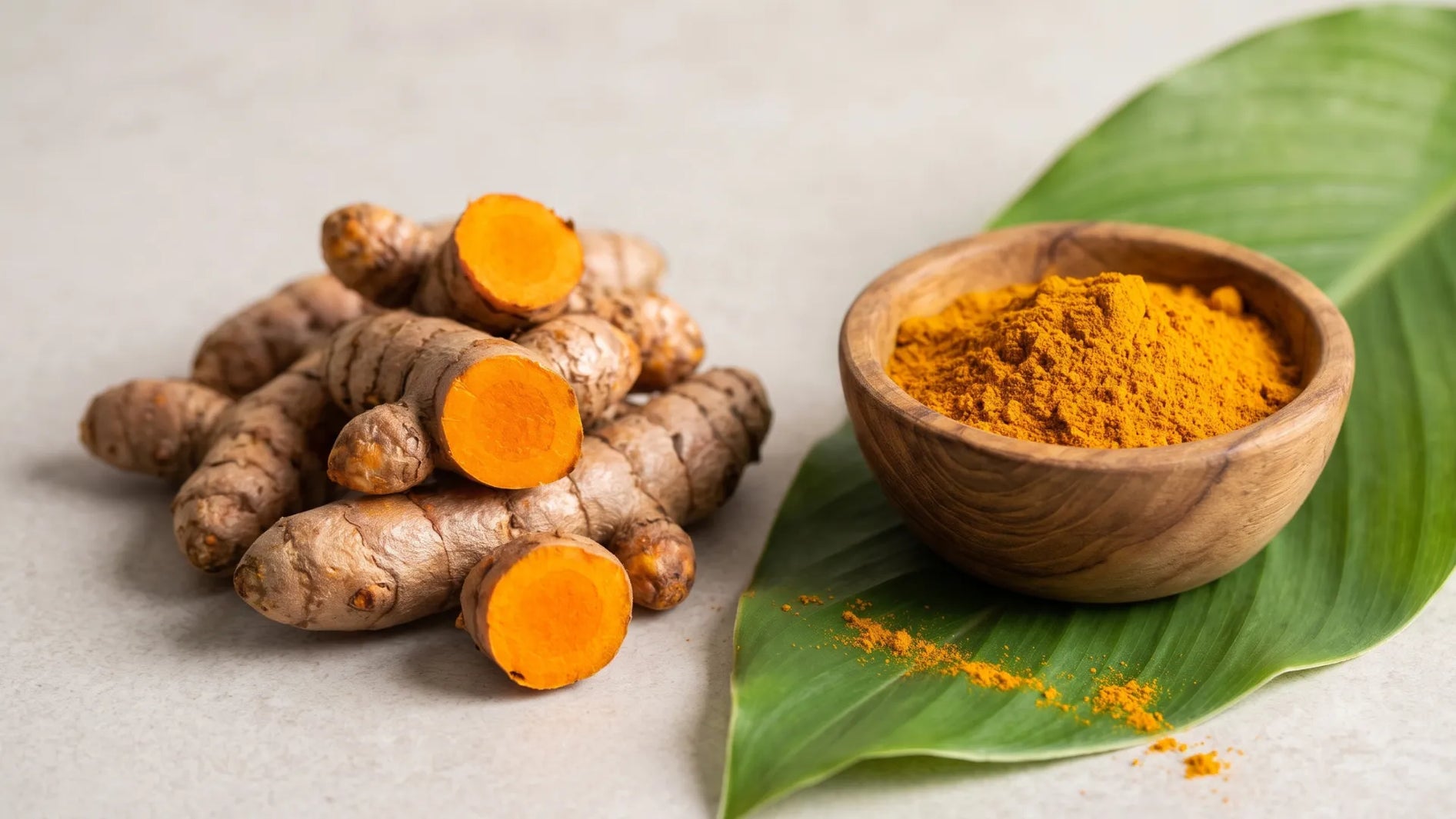 Fresh turmeric root and turmeric powder on a green leaf – turmeric and curcumin for muscle recovery