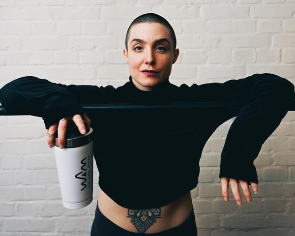 Athlete with a WAM shaker leaning on a bar in front of a white brick wall