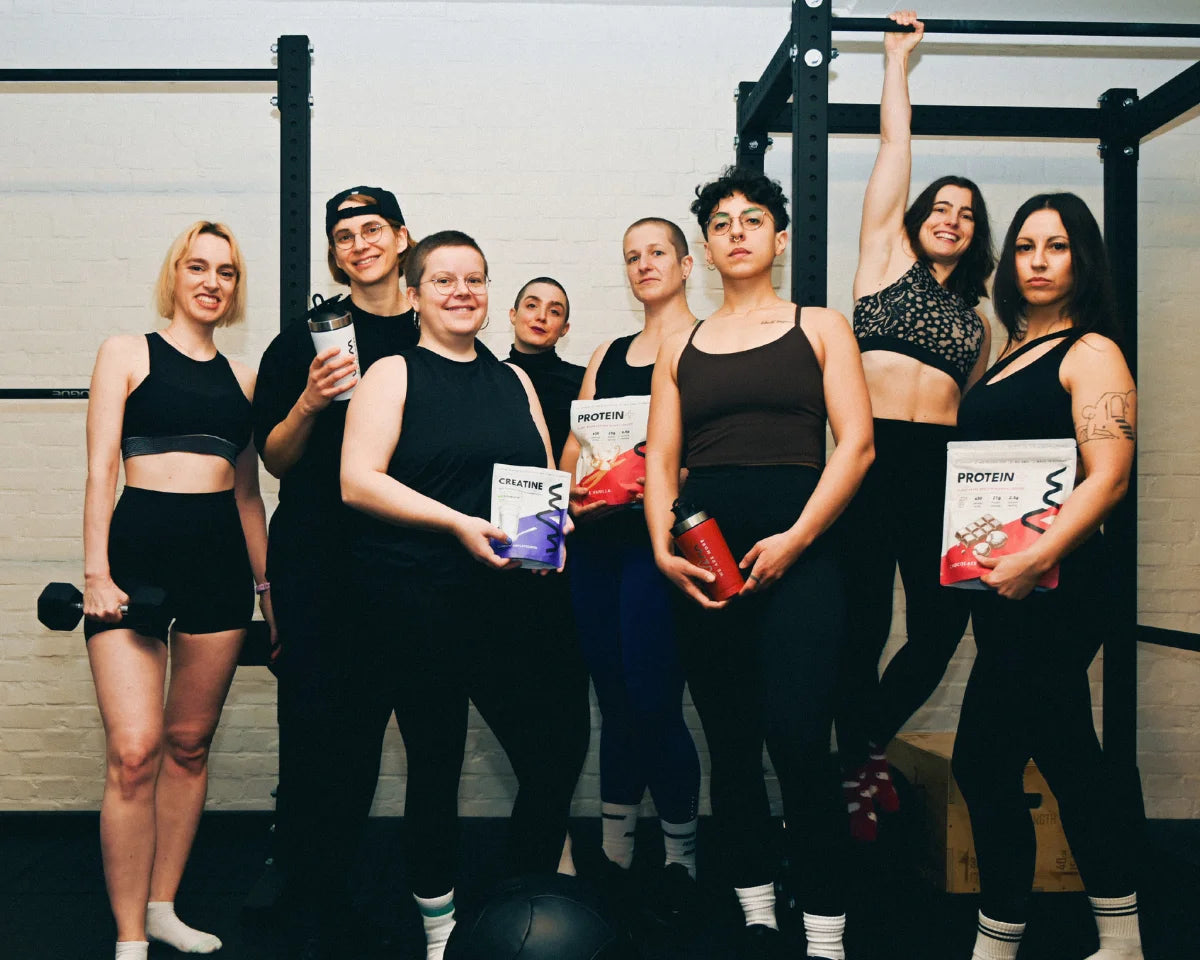 WAM community in the gym holding WAM Protein and Creatine pouches